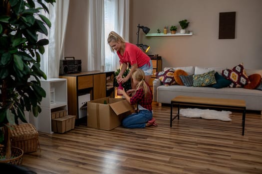 In a beautifully designed and cozy living room, a mother and her daughter find joy in unpacking boxes together