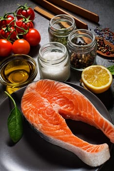 Selection of healthy food. Raw steak of salmon with fresh ingredients on gray background.