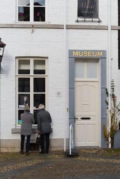 THORN, NETHERLANDS - NOVEMBER 6, 2016: Two unknown elderly women looking through a museum window in the white village of Thorn