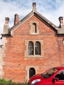 close up of church hall side brick windows above red car  England  UK