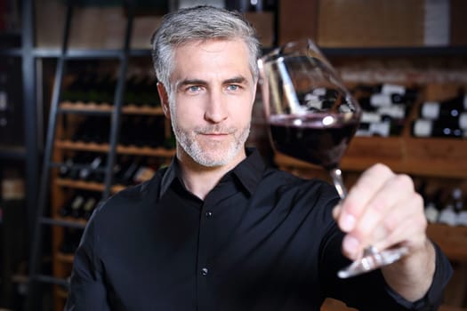 Man poured red wine into a glass. Sommelier selects wine.