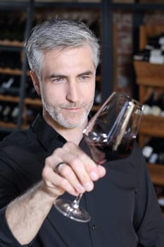 Man poured red wine into a glass. Sommelier selects wine.