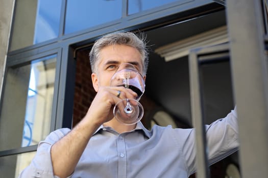 A glass of red wine. Handsome man drinking wine. Man drinking wine.
