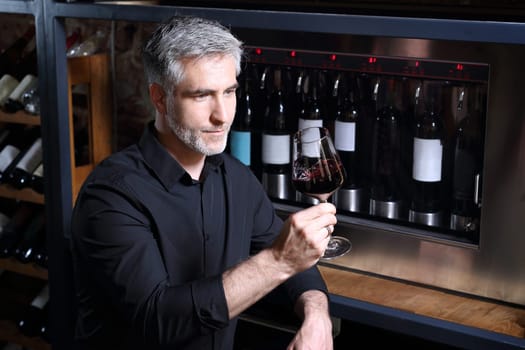 Man poured red wine into a glass. Sommelier selects wine.