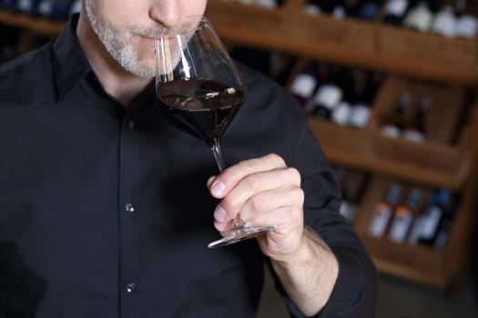 Man poured red wine into a glass. Sommelier selects wine.