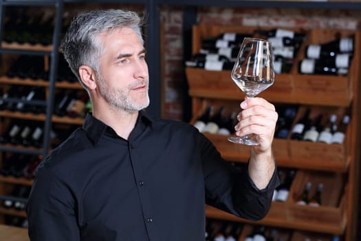 A handsome bartender polishes a glass of wine glasses.