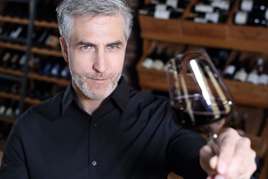 Man poured red wine into a glass. Sommelier selects wine.