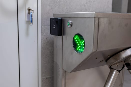 A modern turnstile equipped with a bright green indicator light, clearly signaling that access has been approved