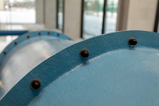 This is a detailed view of a blue industrial pipe, highlighting the fasteners and the unusually smooth surface