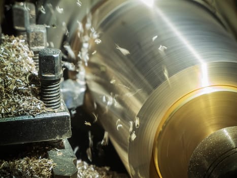 Close-up of the rotary chuck of a manual lathe with clamped material in motion.