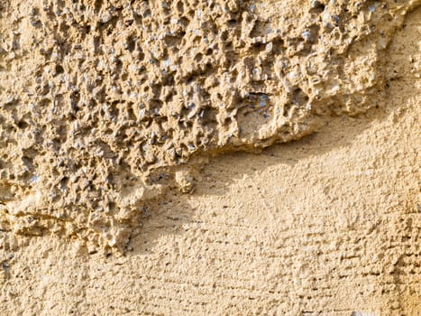 Format-filling view of old masonry with partially detached rough plaster and clinker bricks.
