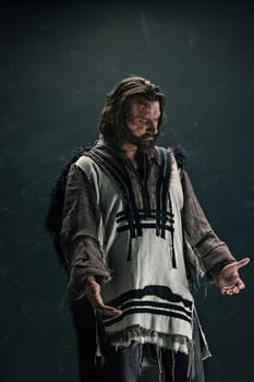 Actor in makeup, a poor man on black studio background. The bum in canvas rags. concept of vagrancy and survival