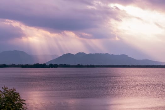 an amazing sunset on Udawalawe lake, colourful pink and pruple sky and reflection in the water, Sri Lanka