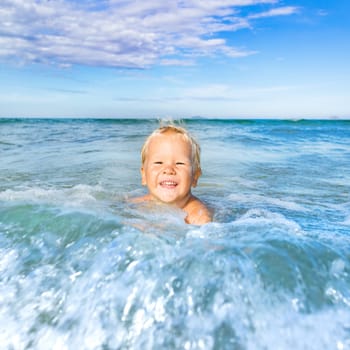 Cute boy plays in a sea