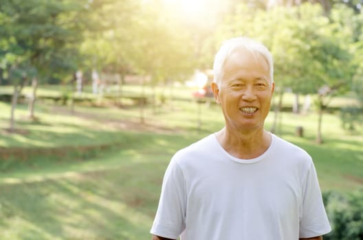 Portrait of white hair Asian old man smiling, standing at outdoor park in morning.