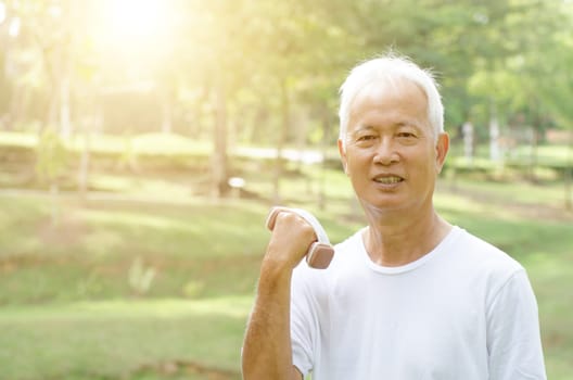 Portrait of healthy gray hair Asian old man with dumbbell at outdoor park in morning.