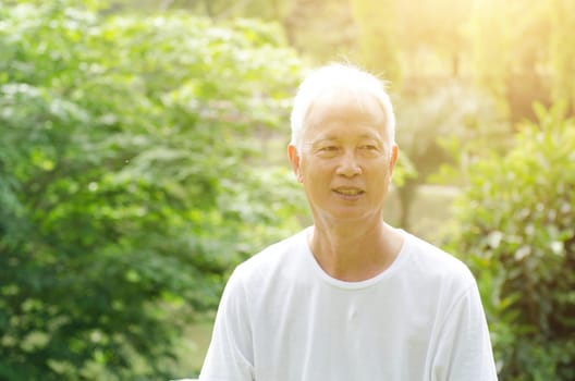 Portrait of white hair Asian senior adult man smiling, standing at outdoor park in morning.