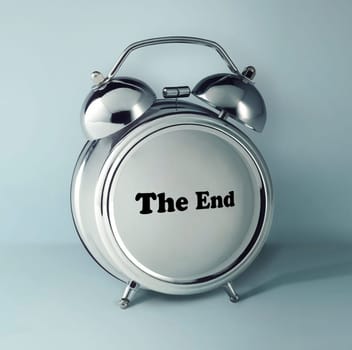 The conceptual image of alarm clock with word THE END on empty clock face against gray studio background. concept of the end of the process