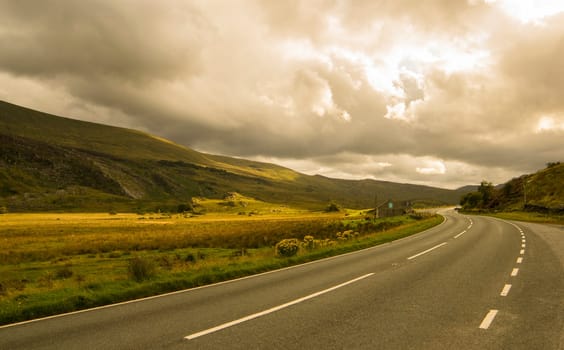 Landscape road in mountains under cloudy sky