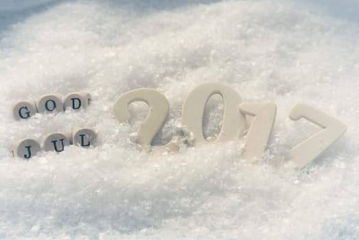 Wooden number 2017 on a snow background with the Scandinavian words God Jul, seasonal or Christmas background