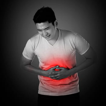 Young asian man have stomach ache, with uneasy face