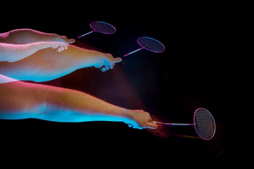 The hands of young man playing badminton over black studio background. Stroboscope shooting technique