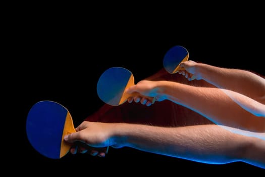 The male hands of table tennis player close up on black background. Stroboscope shooting technique