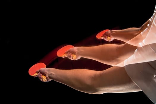 The male hands of table tennis player close up on black background. Stroboscope shooting technique