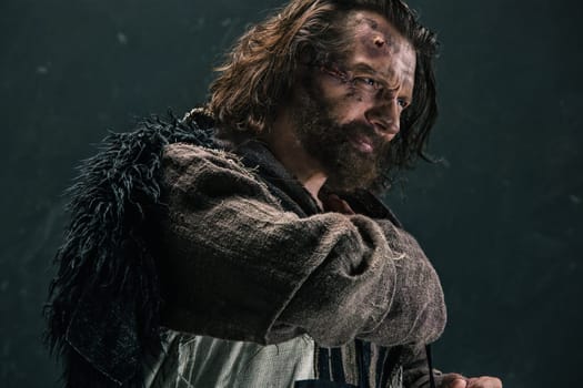Actor in makeup, a poor man on black studio background. The bum in canvas rags. concept of vagrancy and survival. concept of pain and suffering