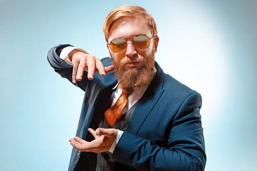 Portrait of a business man presenting something on blue background. Studio shot.