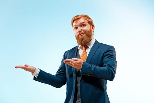 Portrait of a business man presenting something on blue background. Studio shot.