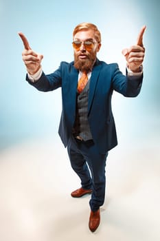 Portrait of a business man presenting something on blue background. Studio shot.