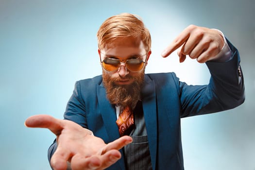 Portrait of a business man presenting something on blue background. Studio shot.