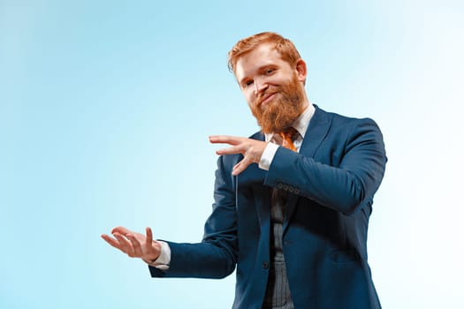 Portrait of a business man presenting something on blue background. Studio shot.