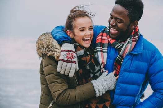 A young couple with arms around each other laughing and having fun.