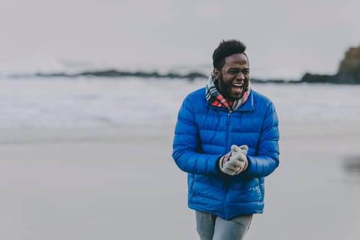 Young man laughing on a winter beach.