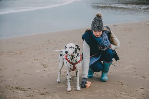 Woman cleaning up after dog on a beach in winter.