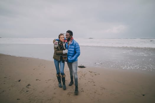 A young couple enjoy a romantic walk on a winter beach in Tynemouth.