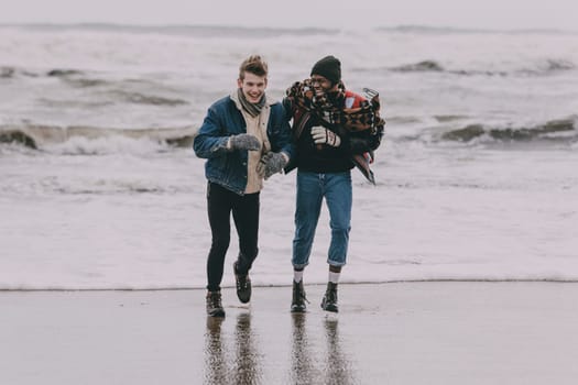 Two friends laughing and having fun on a winter beach.