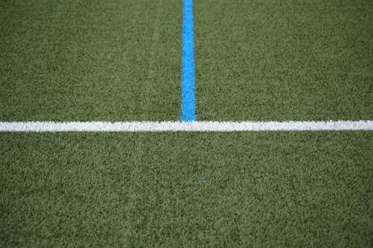 The green lawn of a football field with the sideline and the center line.
