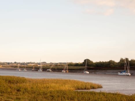 sunset scene over river through country with moored boats and clear sky  England  Essex