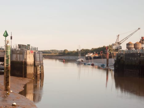 sunset light scene over dock gate open with moored boats river  England  Essex