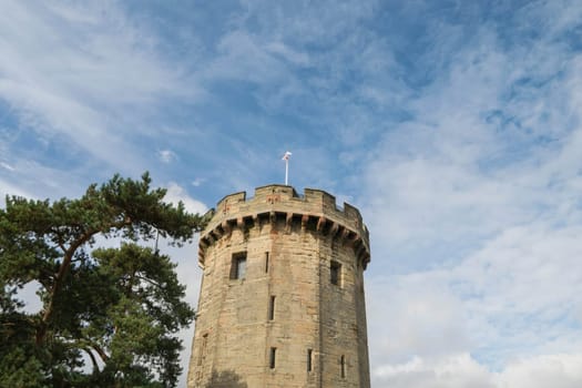 Warwick, United Kingdom - September 19, 2016: View of the Medieval castle tower and gatehouse from within the castle gardens and people enjoying the setting, Warwick, Warwickshire