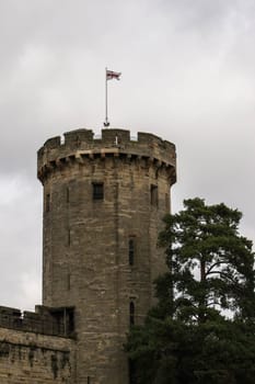 Warwick, United Kingdom - September 19, 2016: View of the Medieval castle tower and gatehouse from within the castle gardens and people enjoying the setting, Warwick, Warwickshire