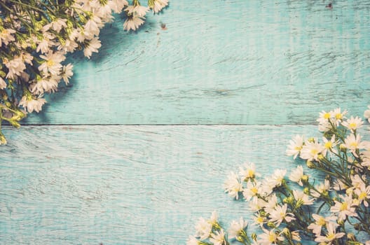 White flowers on blue wooden background. Festive greeting card top with copy space, flat lay. Vintage tone filter.