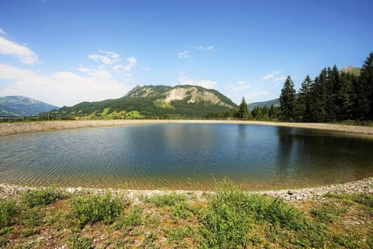 Alpine landscape in summer,in the foreground a storage pond