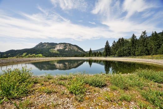 Alpine landscape in summer,in the foreground a storage pond