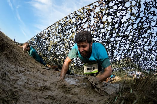 ESTARREJA, PORTUGAL - SEPTEMBER 23: Athletes crawling through mud at the Biorace on september 23, 2017 in Estarreja, Portugal.