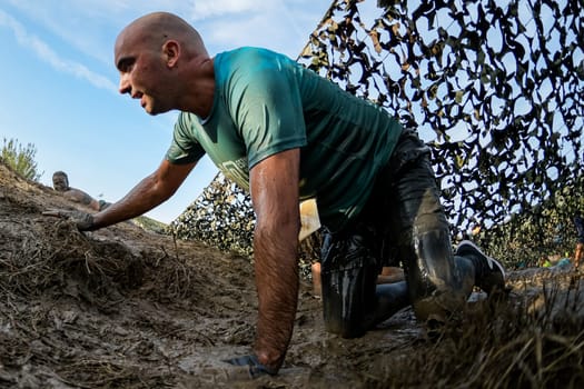 ESTARREJA, PORTUGAL - SEPTEMBER 23: Athletes crawling through mud at the Biorace on september 23, 2017 in Estarreja, Portugal.