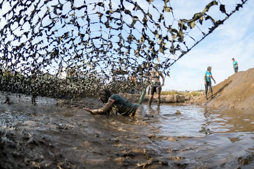 ESTARREJA, PORTUGAL - SEPTEMBER 23: Athletes crawling through mud at the Biorace on september 23, 2017 in Estarreja, Portugal.